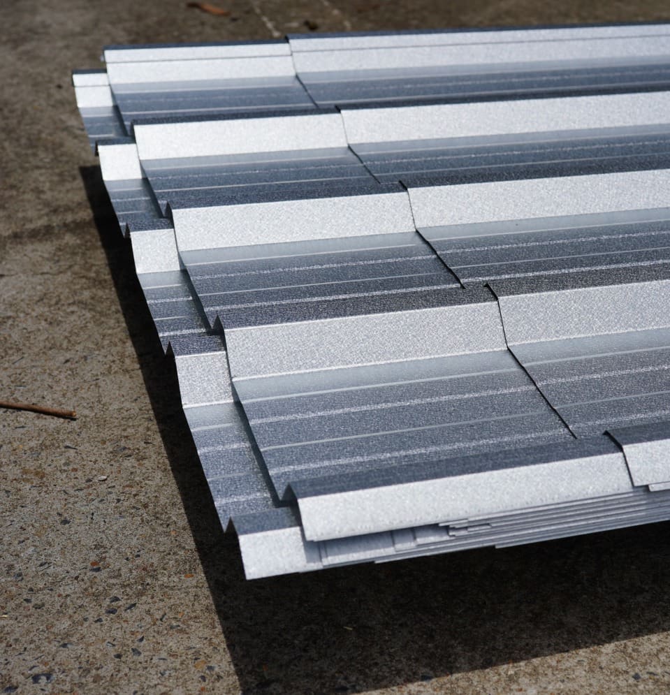 Stacked corrugated metal roofing sheets.