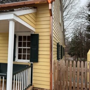 Yellow house with porch and wooden fence.