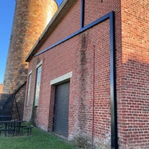 Brick building with round tower and grass.