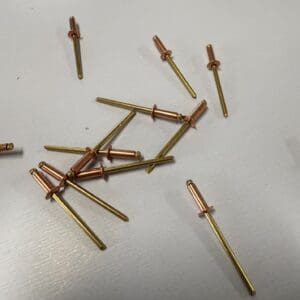 Copper and brass rivets on white surface.