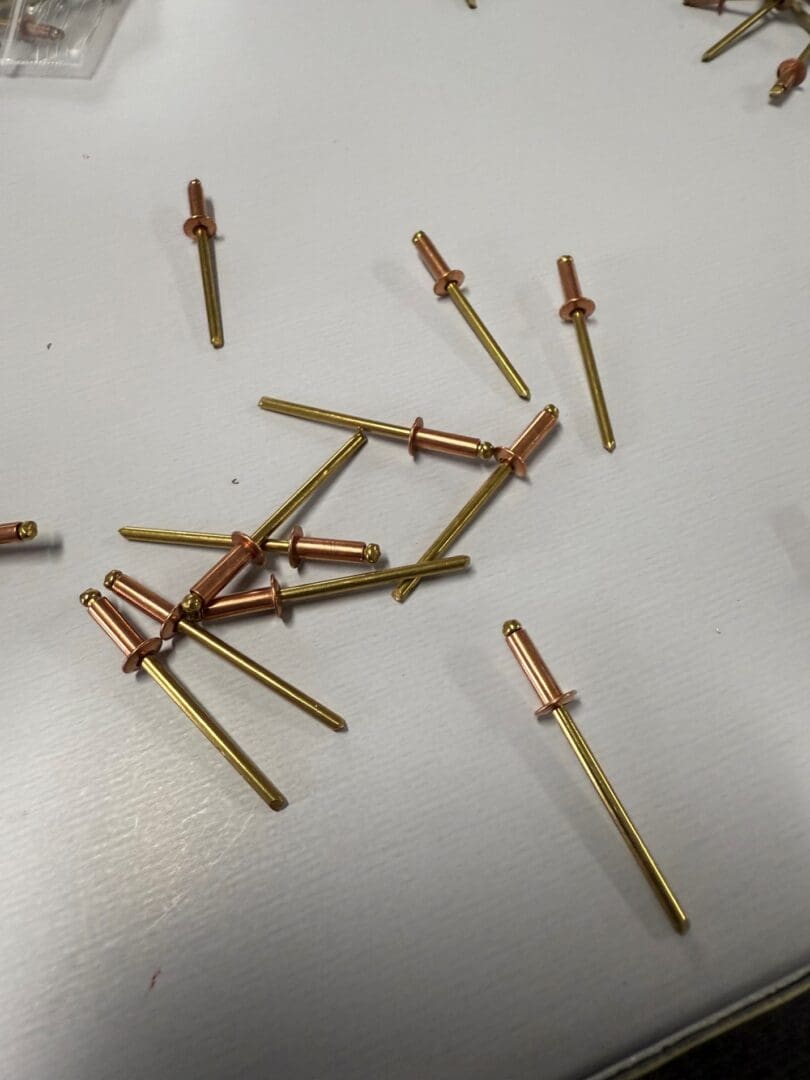Copper and brass rivets on white surface.