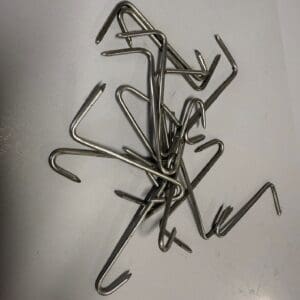 Pile of curved metal hooks on table.