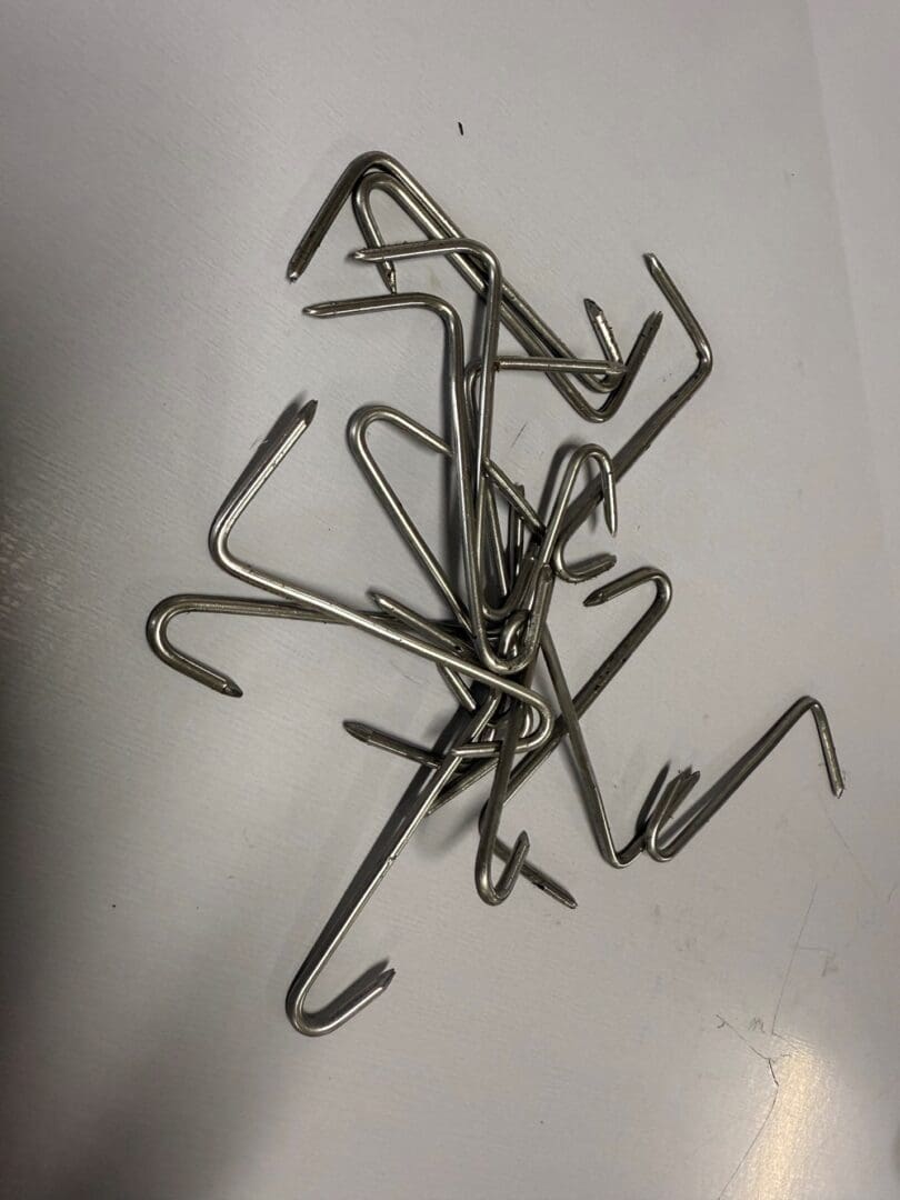 Pile of curved metal hooks on table.