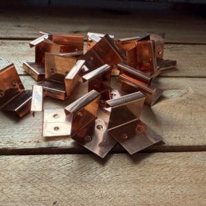 Copper brackets on wooden surface.