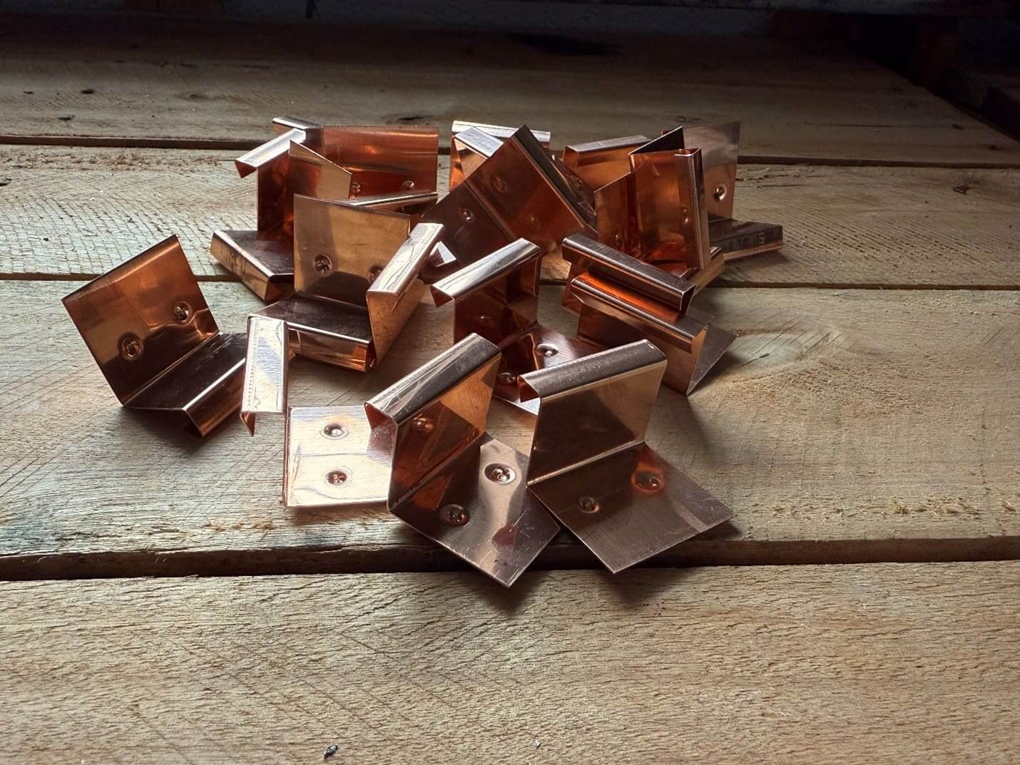 Copper brackets on wooden surface.